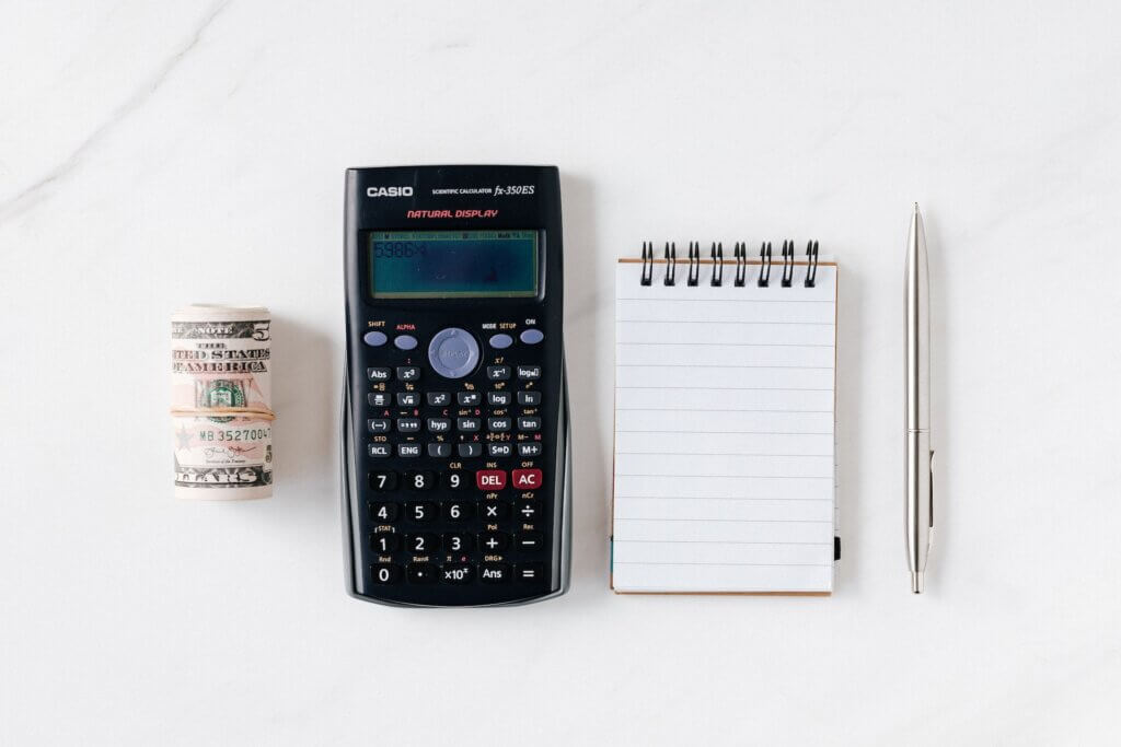 Role of USD, a Casio calculator, a small note pad, and a pen