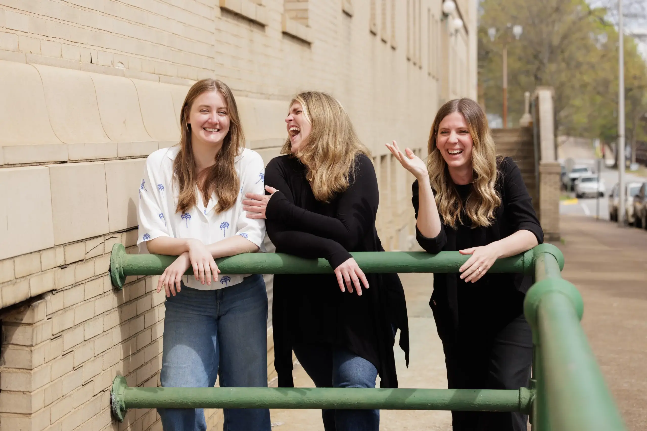 PPC Team standing outside by a building with their arms draped over a safety bar, L-R: Beth Ireland, Tess Little, and Lauren England